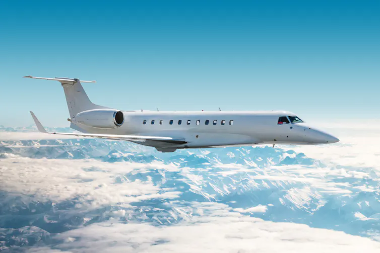 private jet flies above mountains