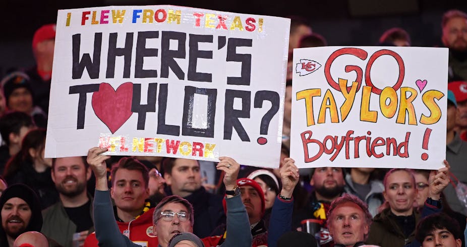 Aficionados al fútbol americano sostienen pancartas en las que se puede leer "¡He volado desde Texas! Where's Taylor?" y "Go Taylor's Boyfriend!" en las gradas de un partido de los Kansas City Chiefs.