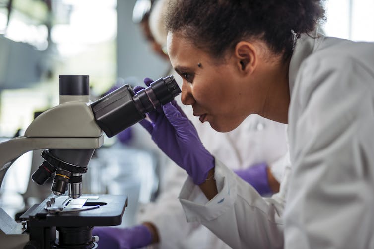 Profile view of scientist looking into a microscope