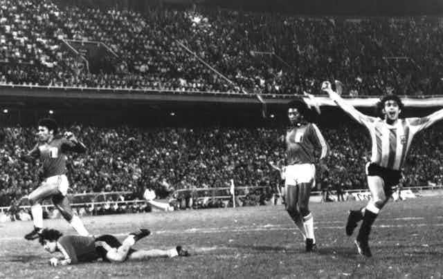 Um jogador da seleção argentina comemora um gol enquanto dois jogadores peruanos e o goleiro no chão observam