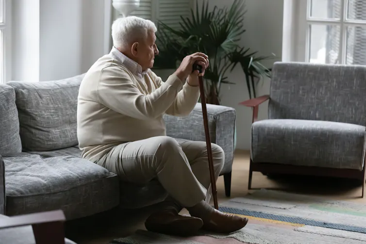 A man sits on a couch looking away into the distance