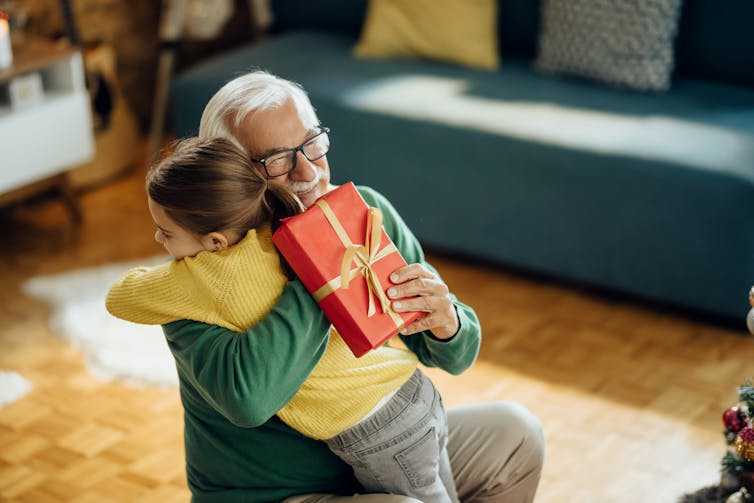A grandfather embraces their grandchild.