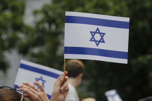 A hand holding an Israeli flag