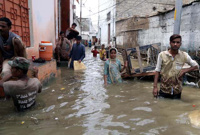 People standing in a flooded street in Pakistan.