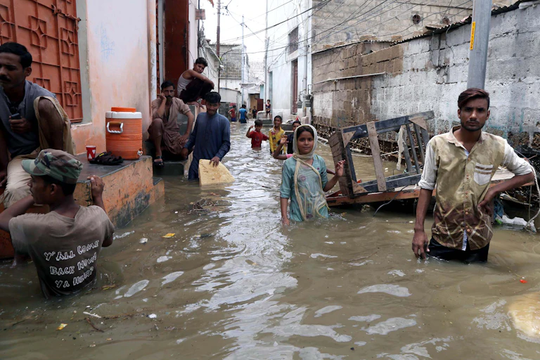 People standing in a flooded street in Pakistan.