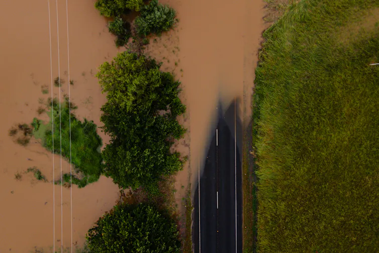 Aerial view of a paved road partially submerged in muddy water