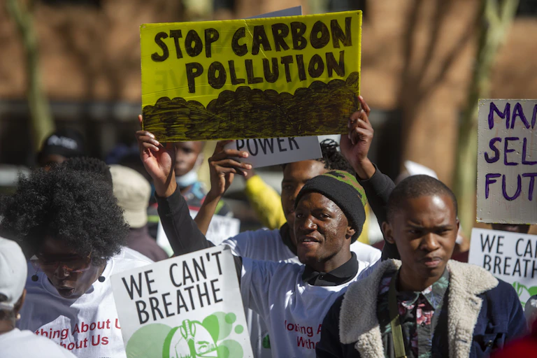Men and women holding up placards reading 'We can't breathe' and 'Stop Carbon Pollution'