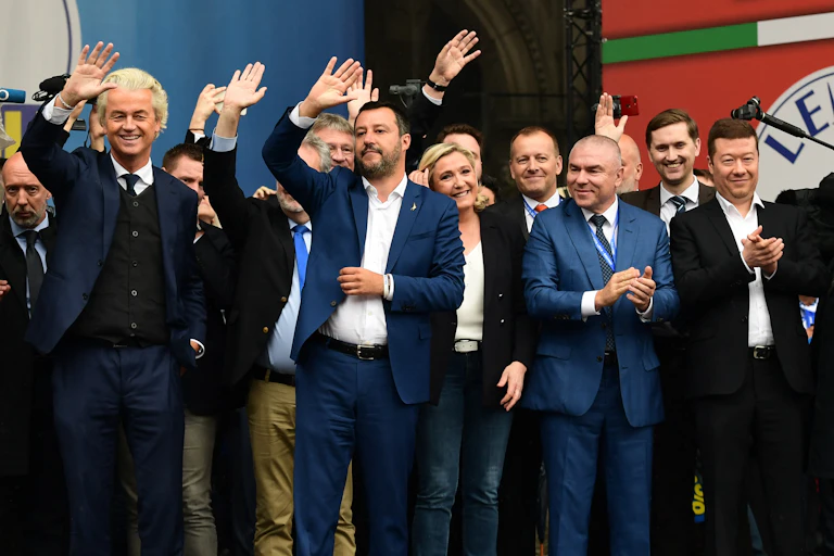 Plusieurs personnes saluent la foule depuis une tribune