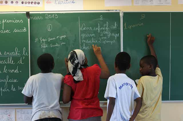 Des élèves écrivent sur un tableau dans une salle de classe d'une école de Mayotte
