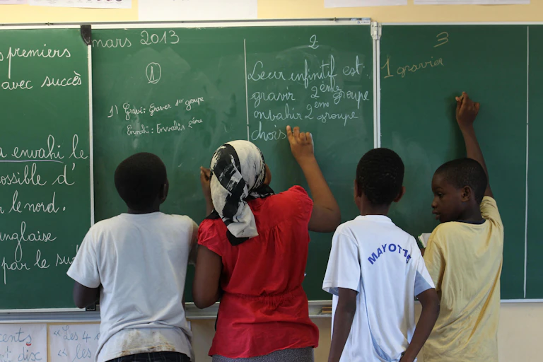 Des élèves écrivent sur un tableau dans une salle de classe d'une école de Mayotte