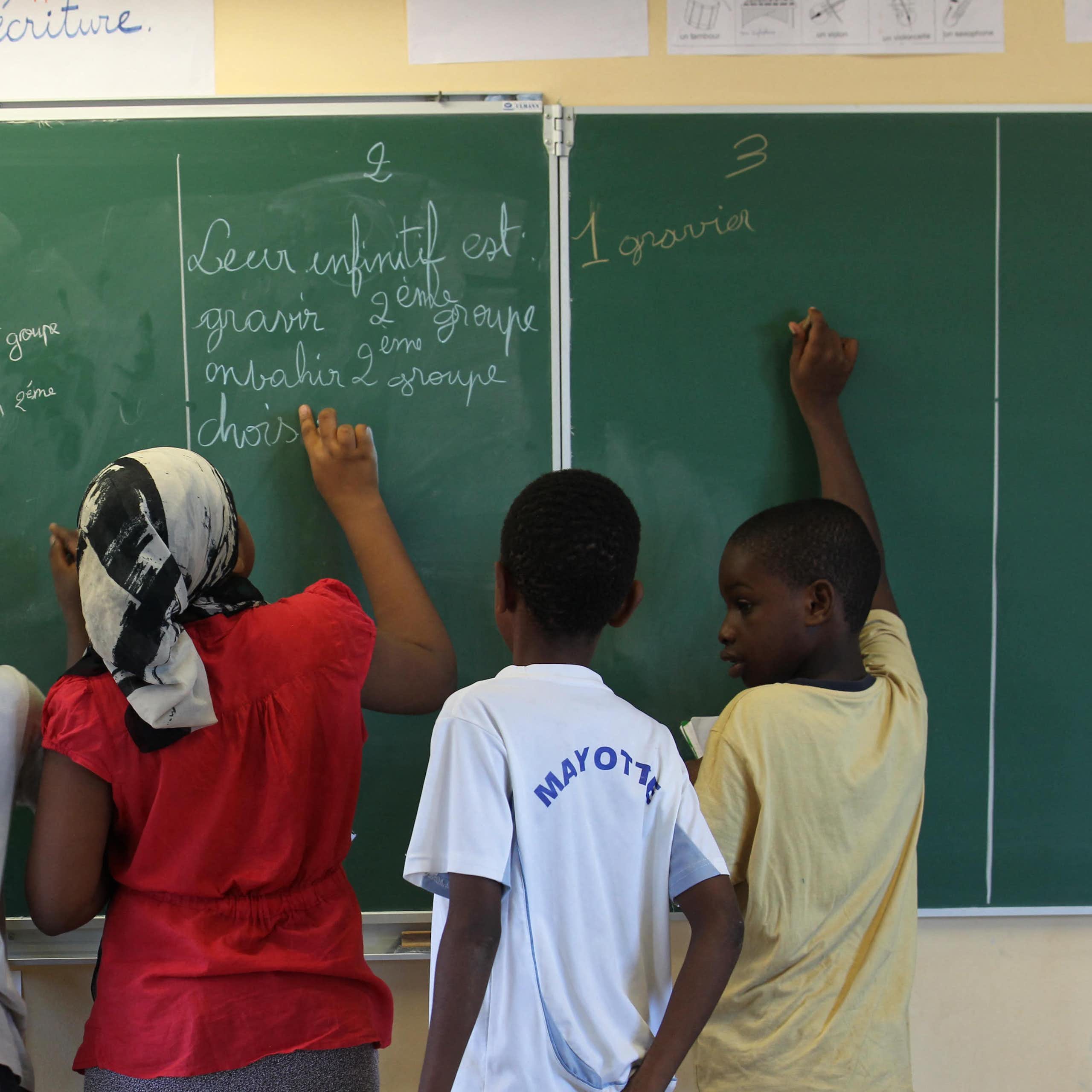 Des élèves écrivent sur un tableau dans une salle de classe d'une école de Mayotte