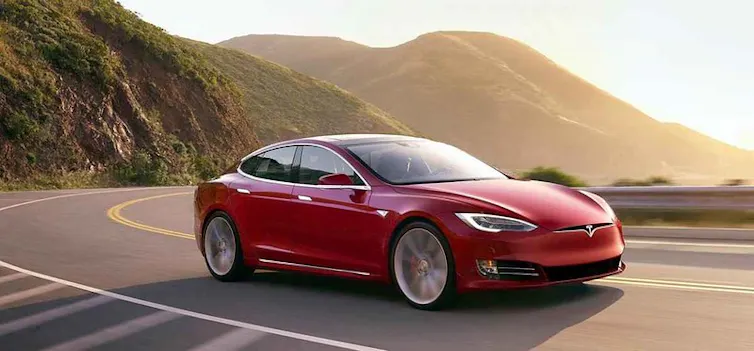 Une Tesla roule sur une route côtière