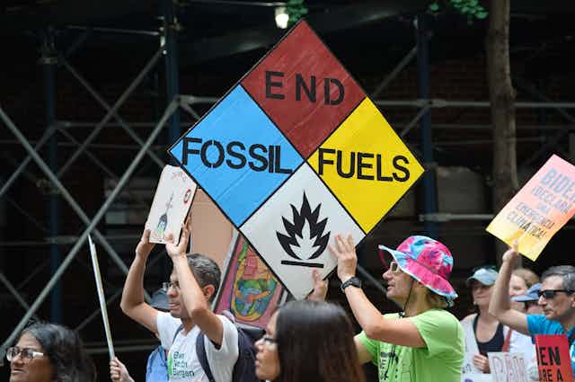 Protesters in a climate march hold a sign saying 'end fossil fuels'.