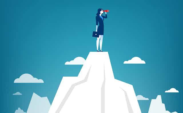 Woman in blue suit with binoculars standing on a mountain.