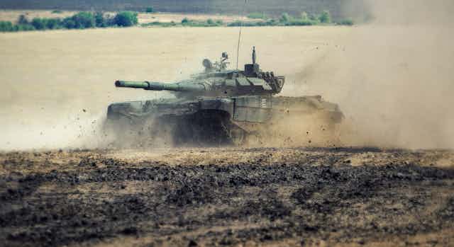 A Russian battle tank moving through a field.