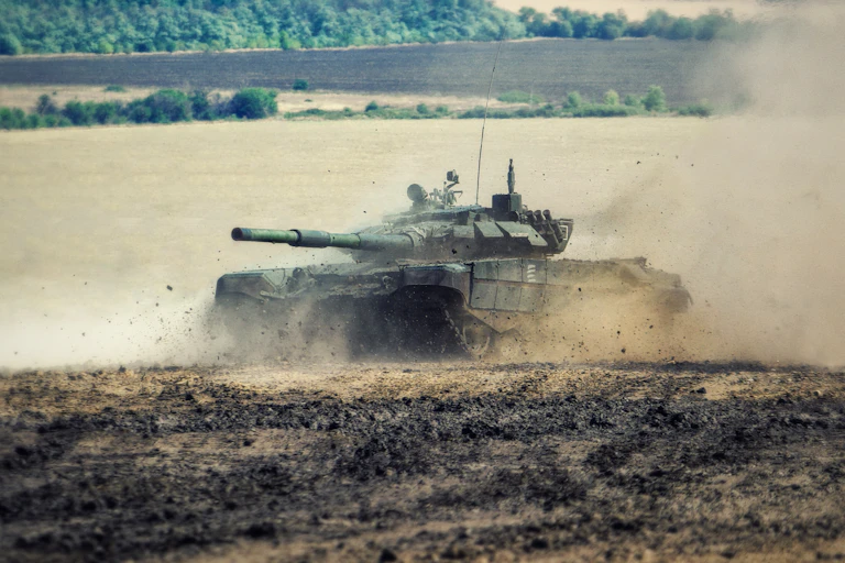 A Russian battle tank moving through a field.