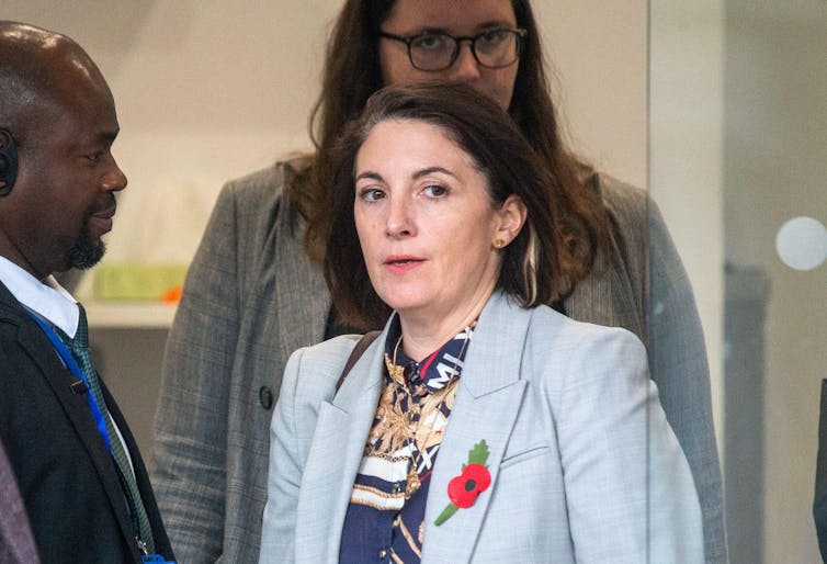 Helen MacNamara in grey suit jacket with poppy on lapel.