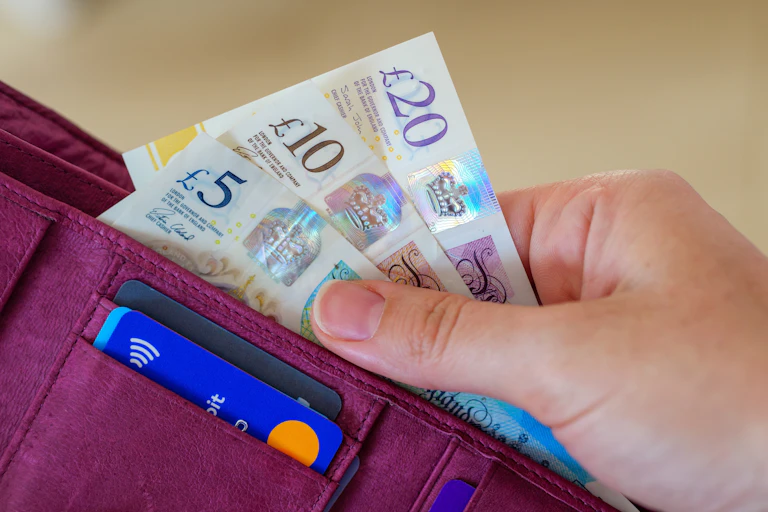 Close up of hand taking Sterling notes out of wallet