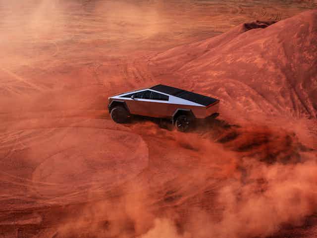 The Tesla Cybertruck driving in sand.