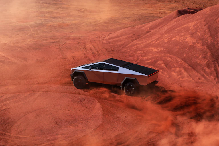 The Tesla Cybertruck driving in sand.