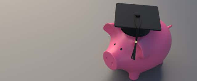 Piggy Bank with college graduate cap, gray background.