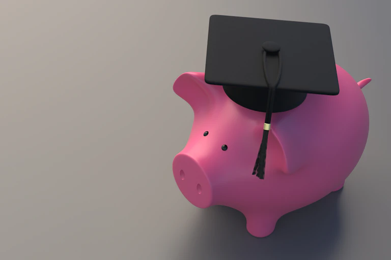 Piggy Bank with college graduate cap, gray background.