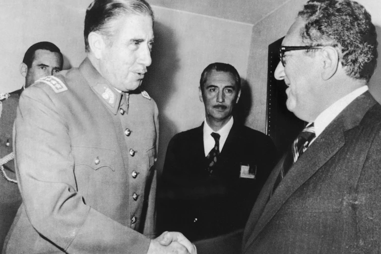 Man with mustache shakes Kissinger's hand