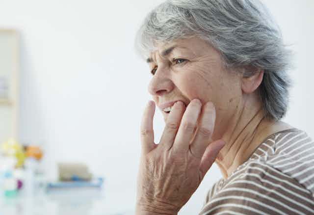 Older woman feels tooth, looking worried