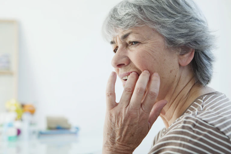 Older woman feels tooth, looking worried