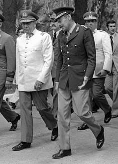 Two men in military uniforms chat in a black and white photo.