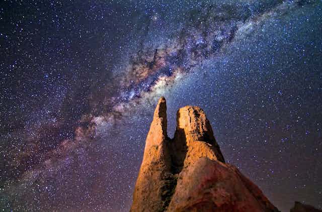 Night time photo showing a rock formation with the Milky Way in the background