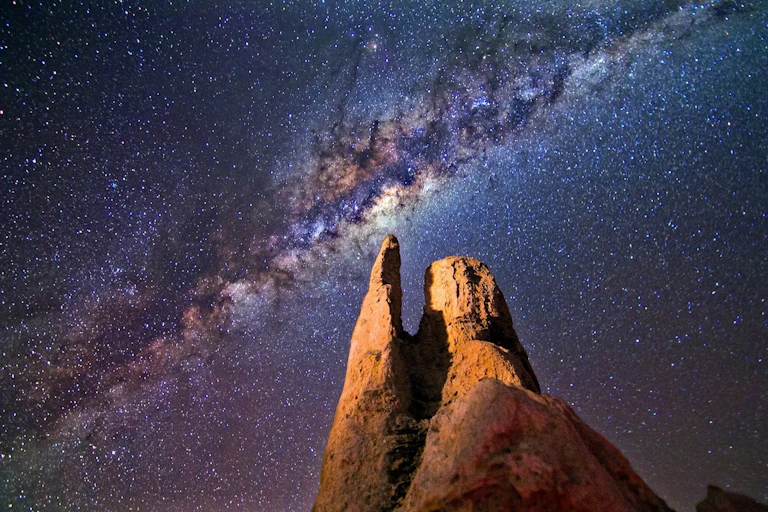 Night time photo showing a rock formation with the Milky Way in the background