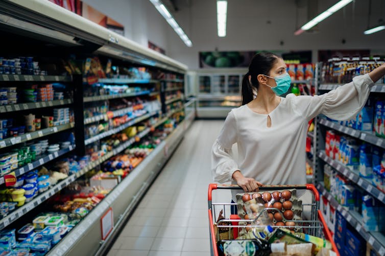 A woman in the supermarket wearing a mask.