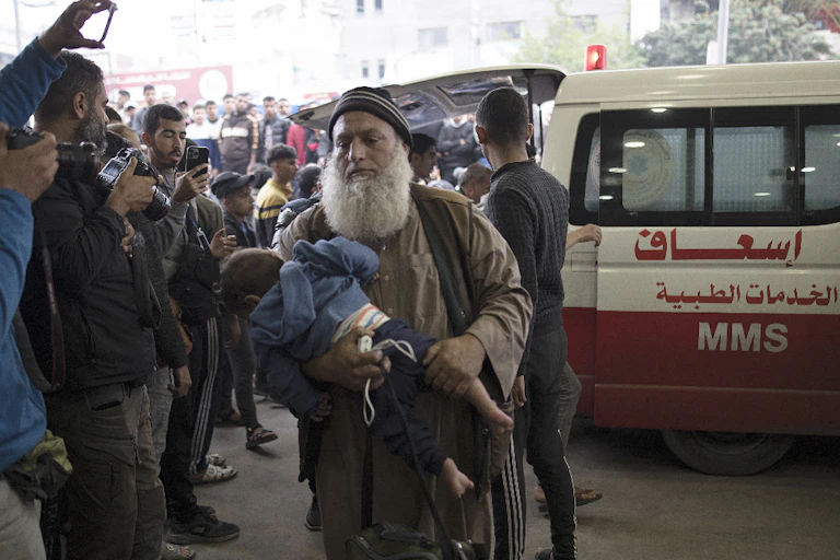 An elderly man walks away from an ambulance at a crowded hospital in Gaza.