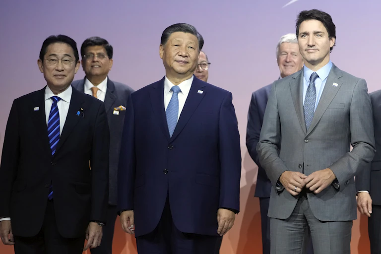 Men in suits stand on a stage smiling.