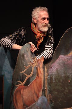 A striking older man – John Byrne – with the set design he created for a play.