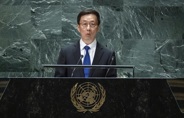 A man stands at a podium with the United Nations insignia and speaks into a microphone.