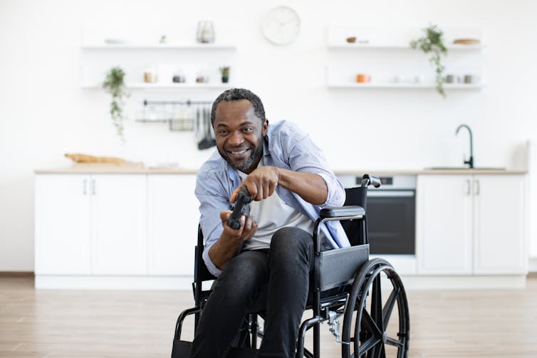 a man in a wheelchair with a game controller