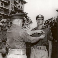 Black and white photo of a man in uniform and a second man pinning a medal on him