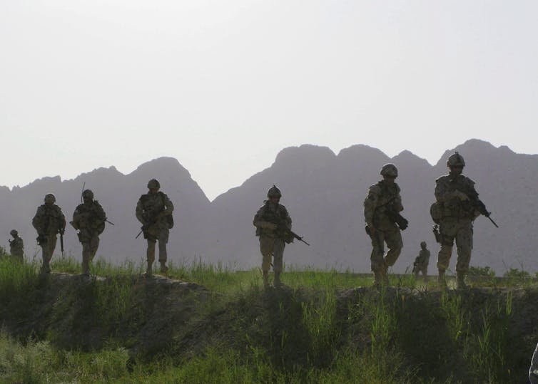 A line of soldiers silhouetted against in a mountain landscape