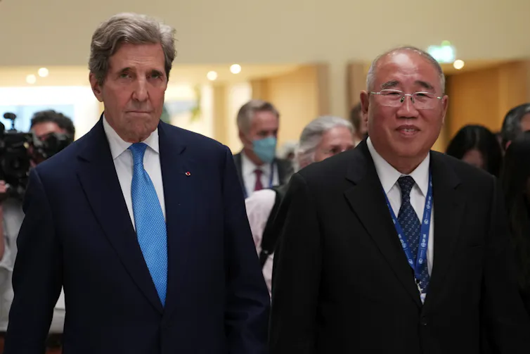 Two men seen walking towards the camera in front of a group of people.
