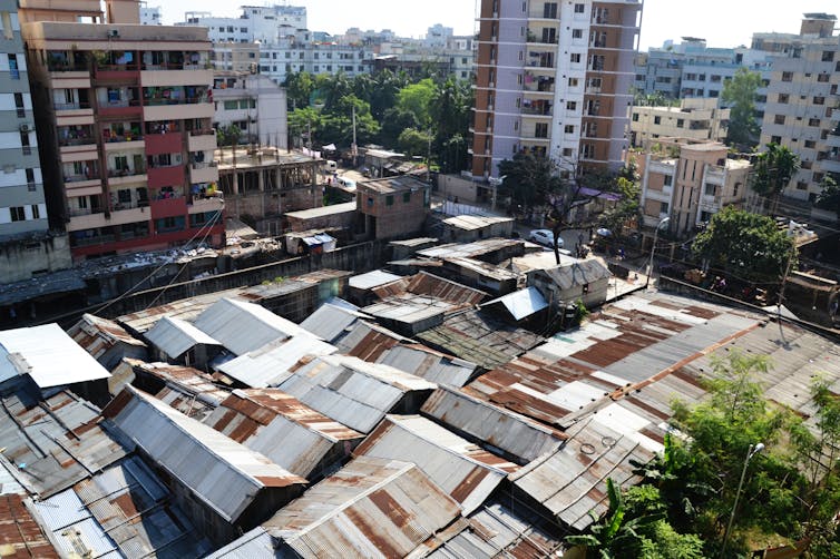 Aerial view of a slum with high-rise buildings bordering it.