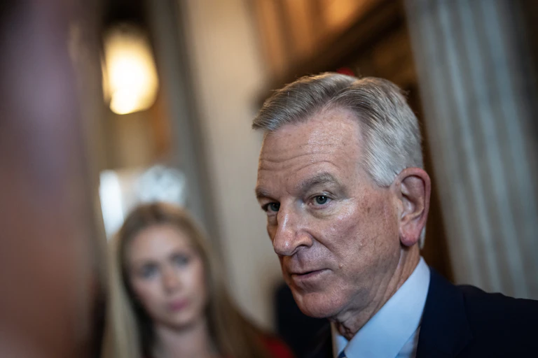 A white man with gray hair is talking with reporters.