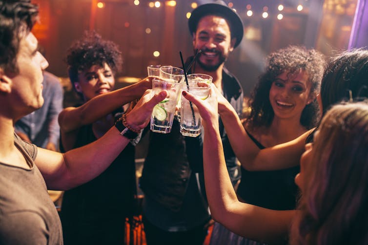 A group of friends clinking their drinks at a nightclub or bar.