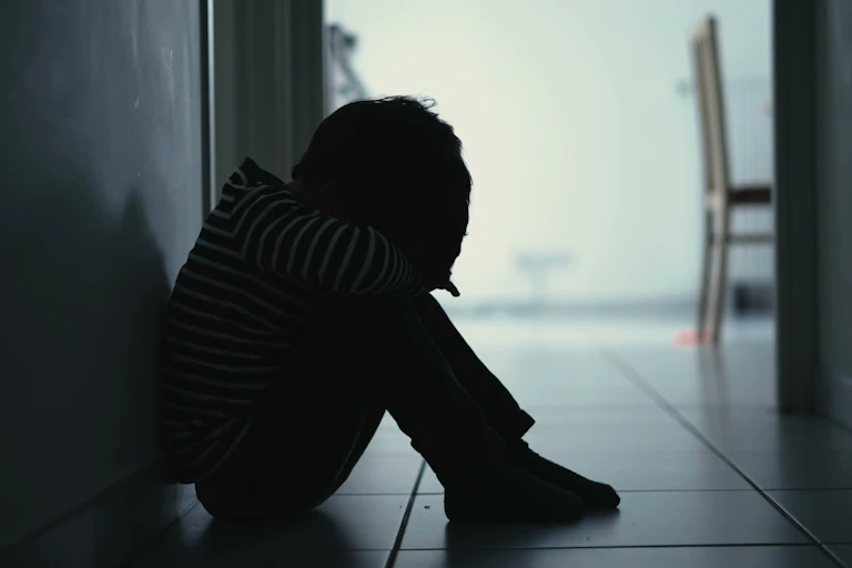 Child sitting in dark hallway