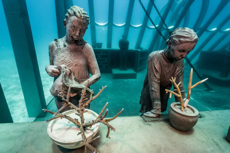 Two sculptures look on growing reefs.