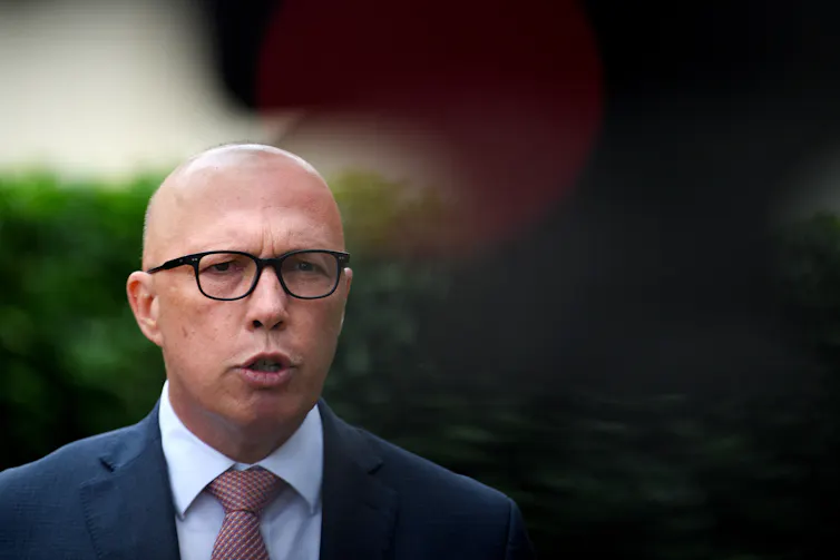 A man in glasses and a suit addresses the media