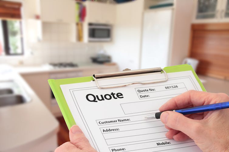 Person writing on a form attached to a clipboard bearing the word ''quote''