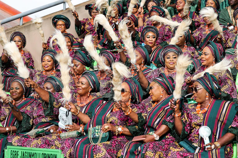 Women in colourful fabrics raising horse tail