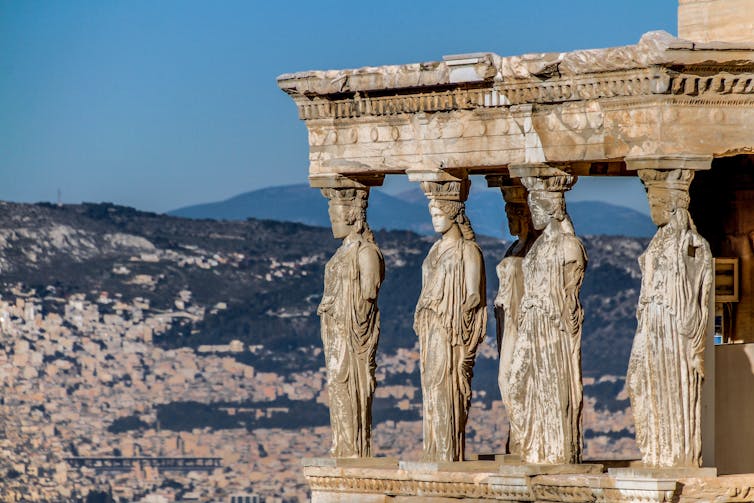Caryatids on the temple with Athens in the background.